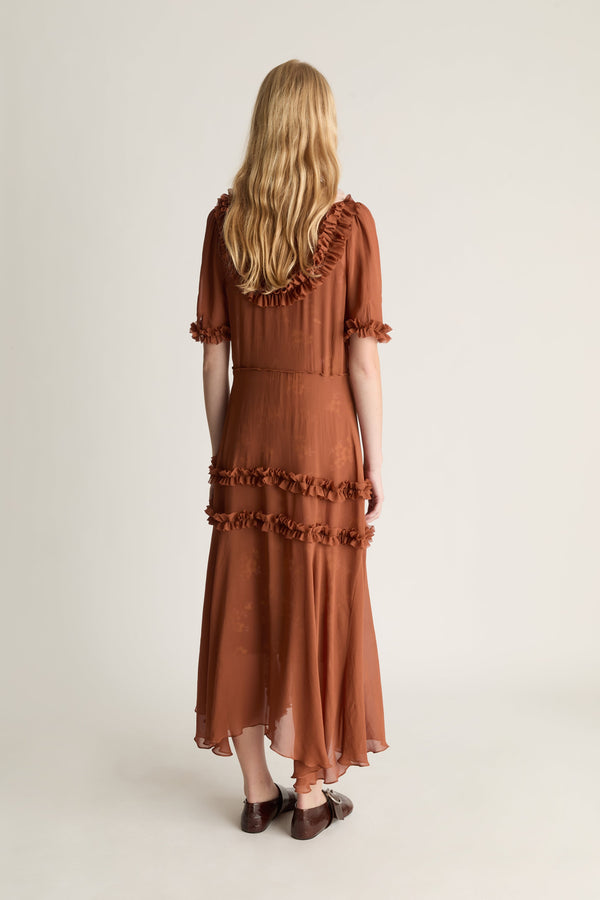 Woman wearing a brown dress with ruffled details on a white background