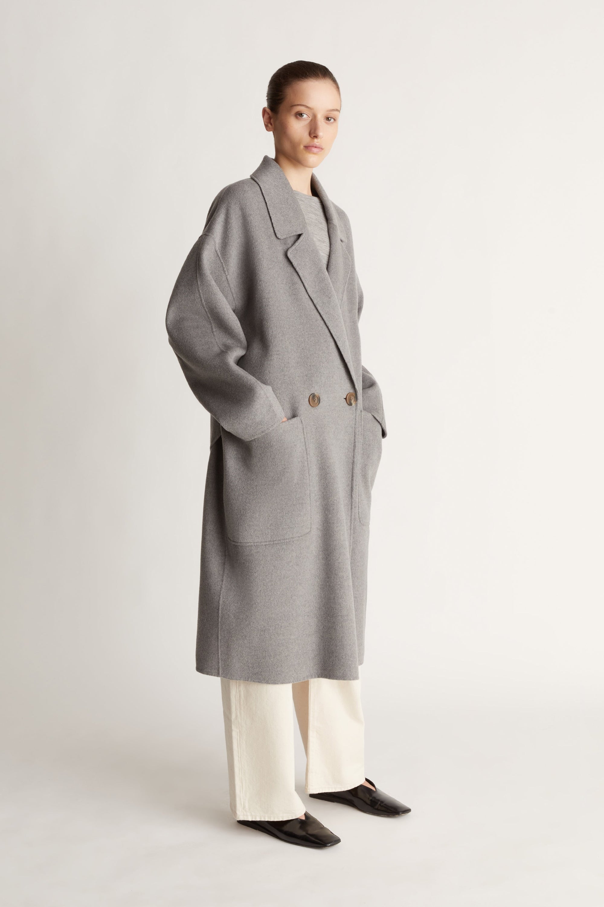Person wearing a gray coat on a plain background