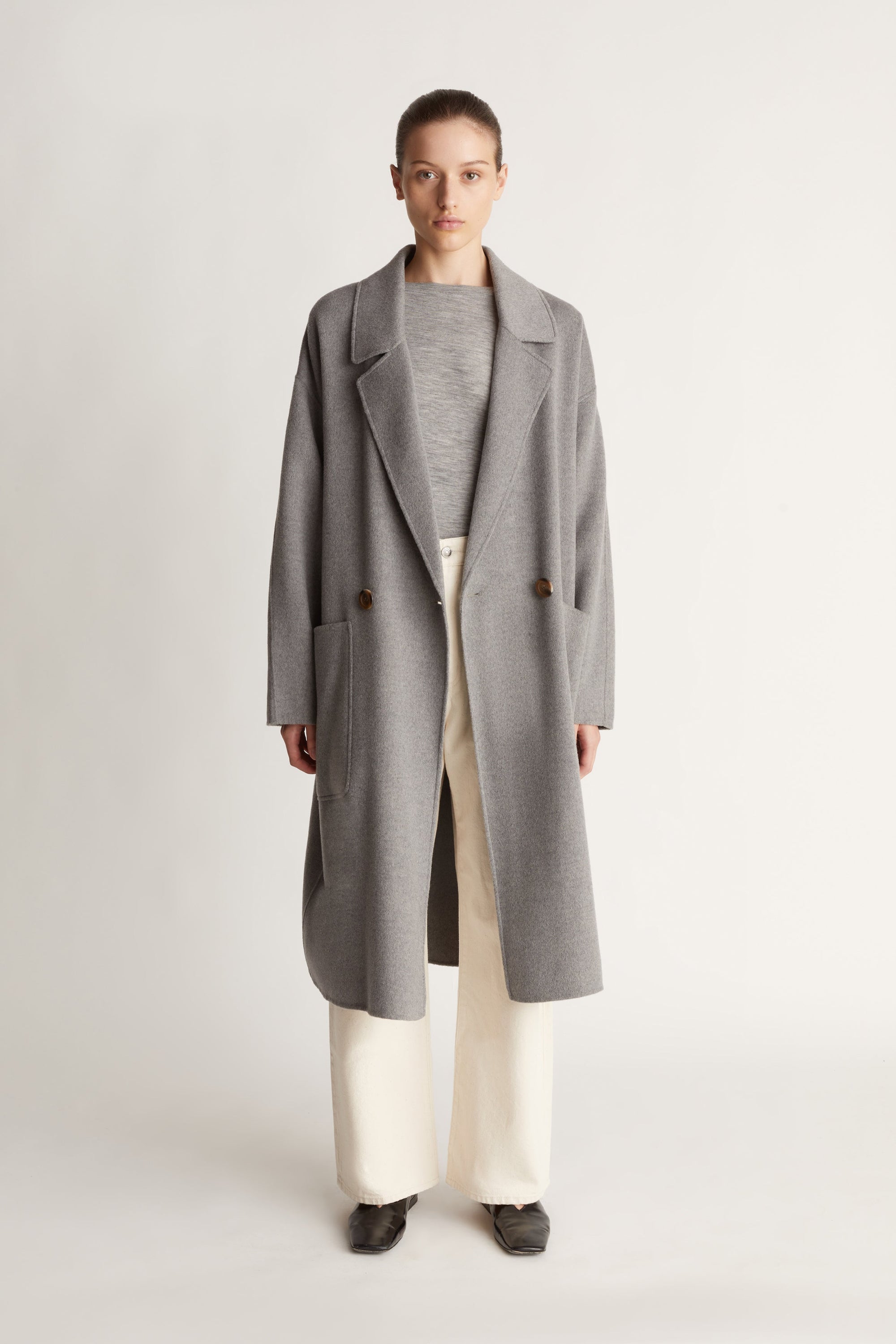 Person wearing a gray coat on a plain background