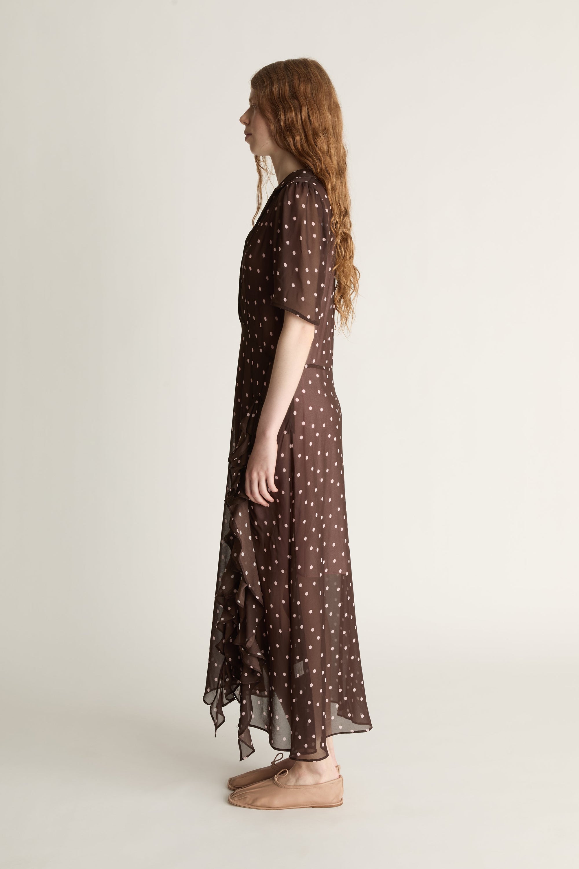 Woman wearing a brown polka dot dress on a white background