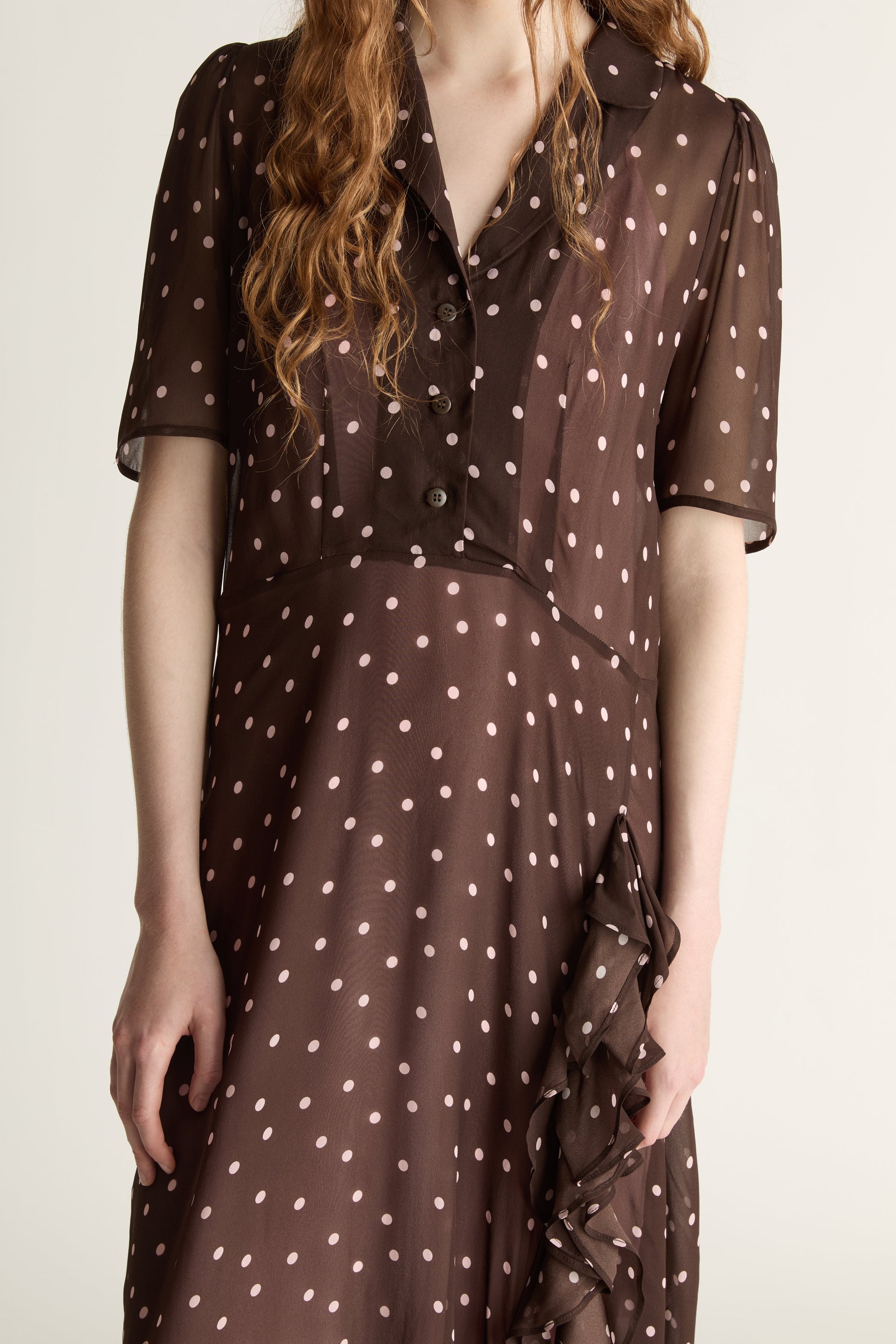 Woman wearing a brown polka dot dress on a white background
