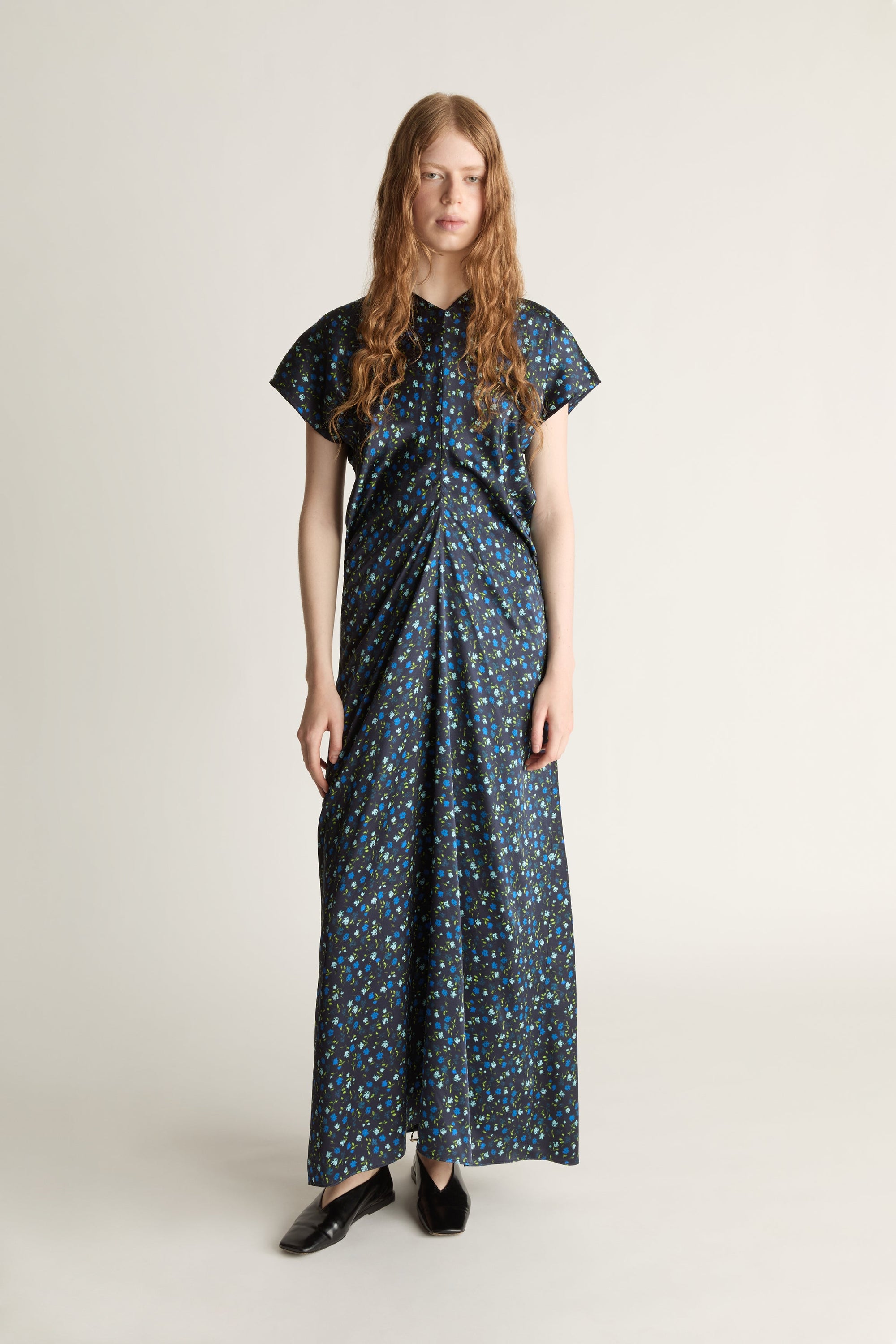 Woman wearing a long, patterned blue dress on a plain background