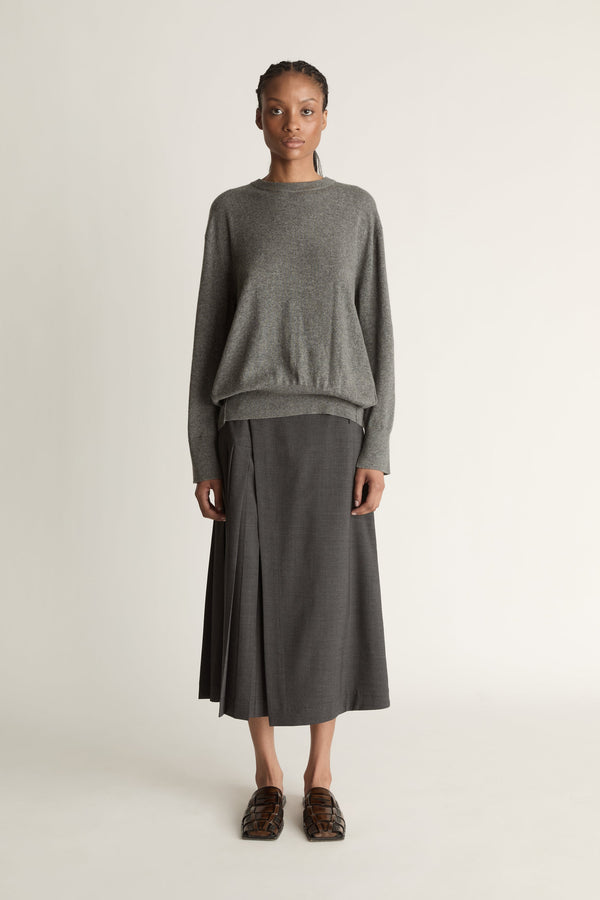 Woman wearing a gray sweater and skirt on a white background