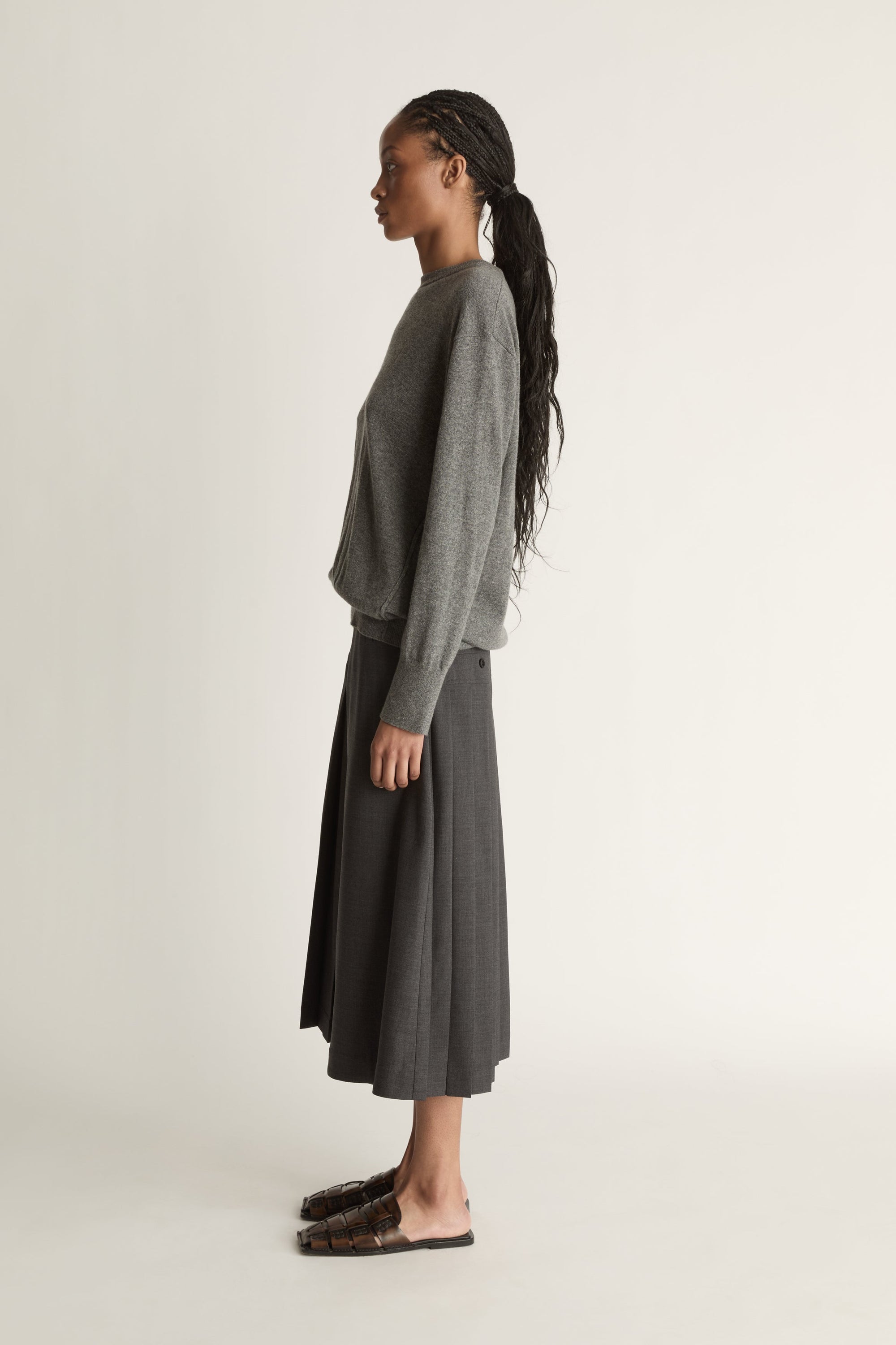 Woman wearing a gray sweater and dark gray skirt on a white background