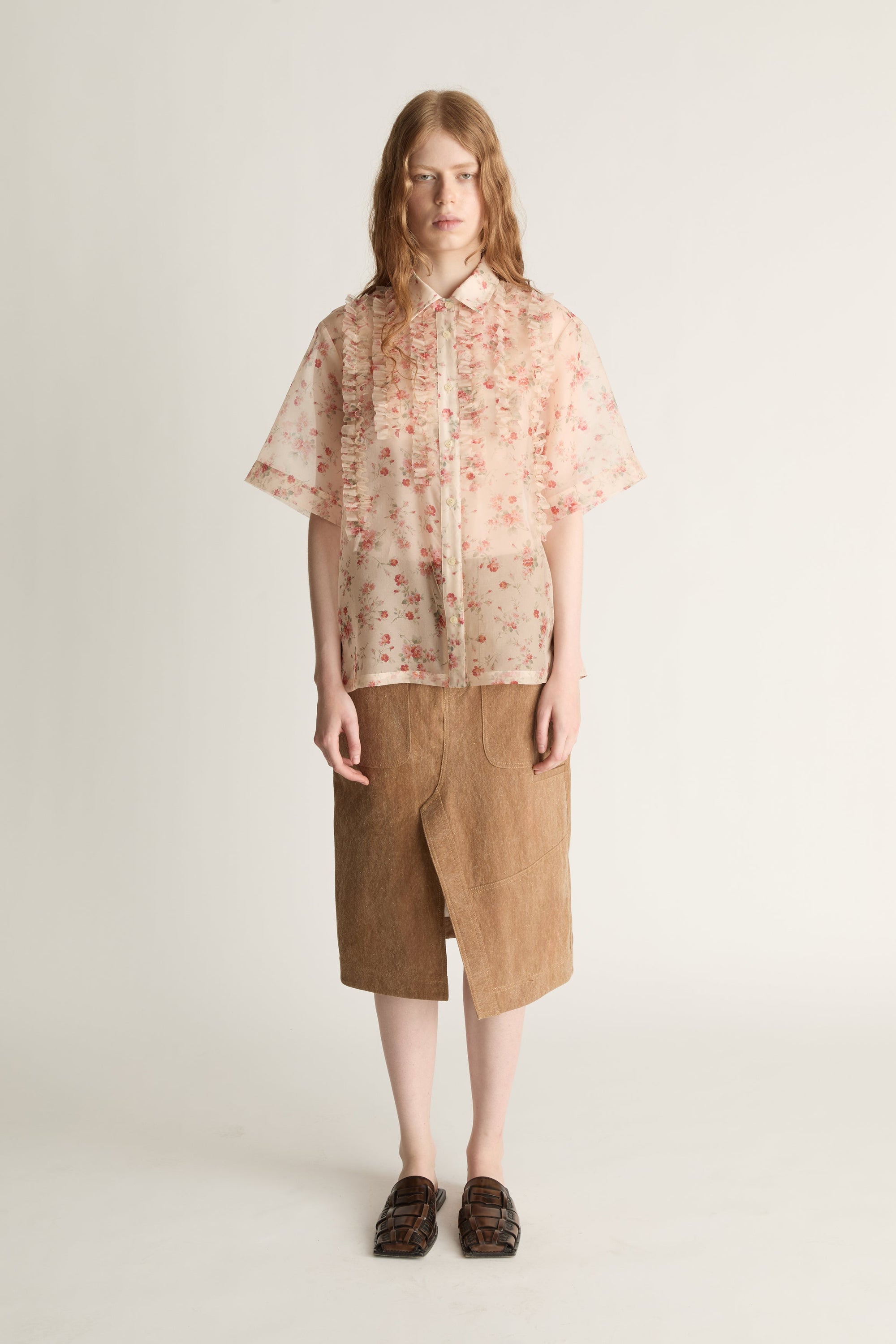 Person wearing a floral blouse and brown skirt on a white background