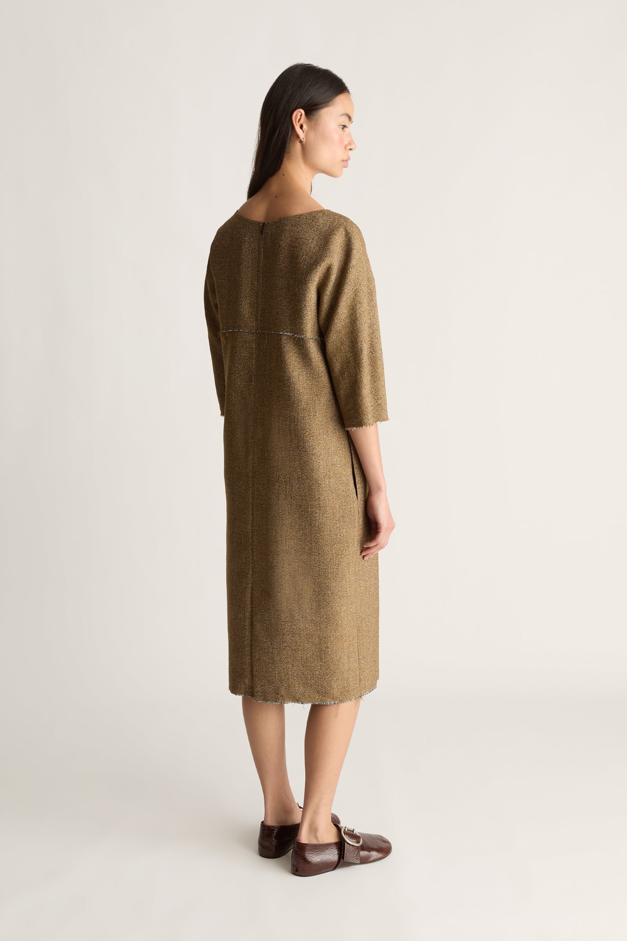 Back view image of a woman wearing a nutmeg coloured midi dress with 3/4 length sleeves on a white background