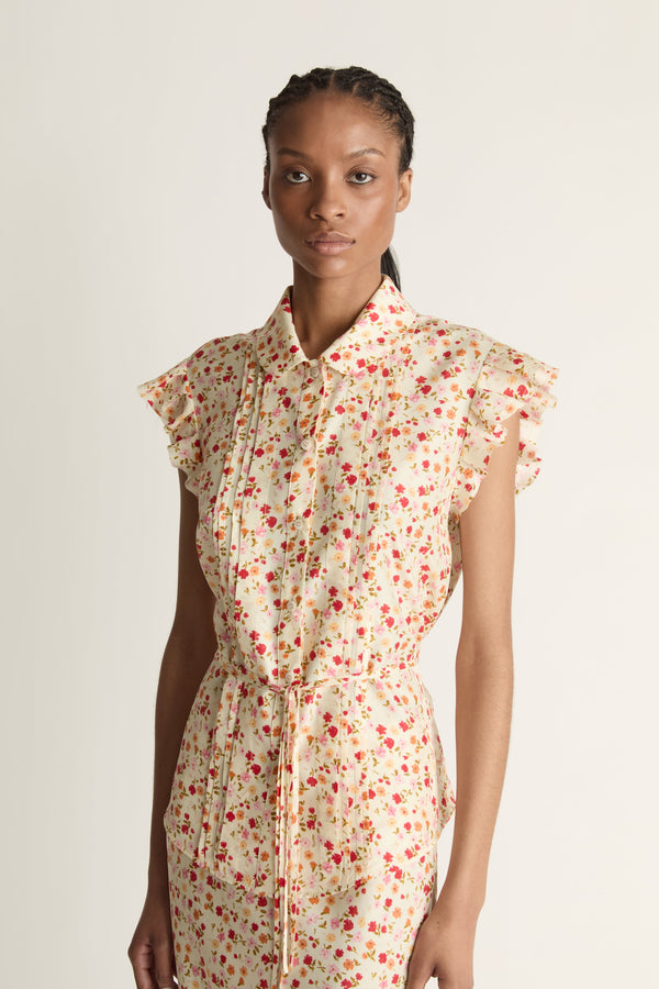 A woman wearing a floral shirt and skirt on a plain background