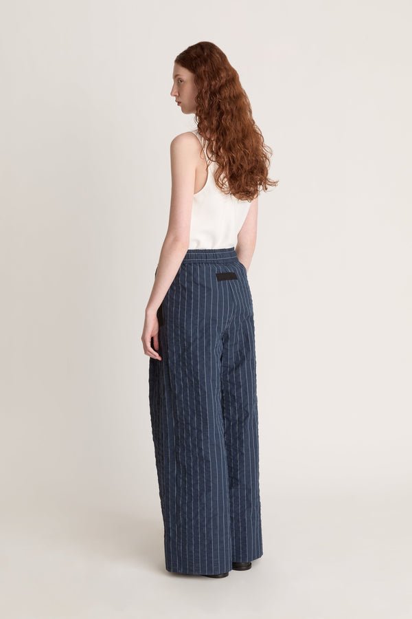 Woman wearing a white top and blue striped pants on a white background