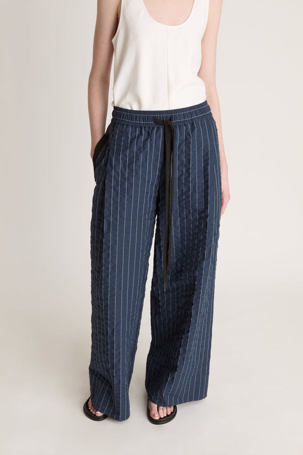 Woman wearing a white top and blue striped pants on a white background