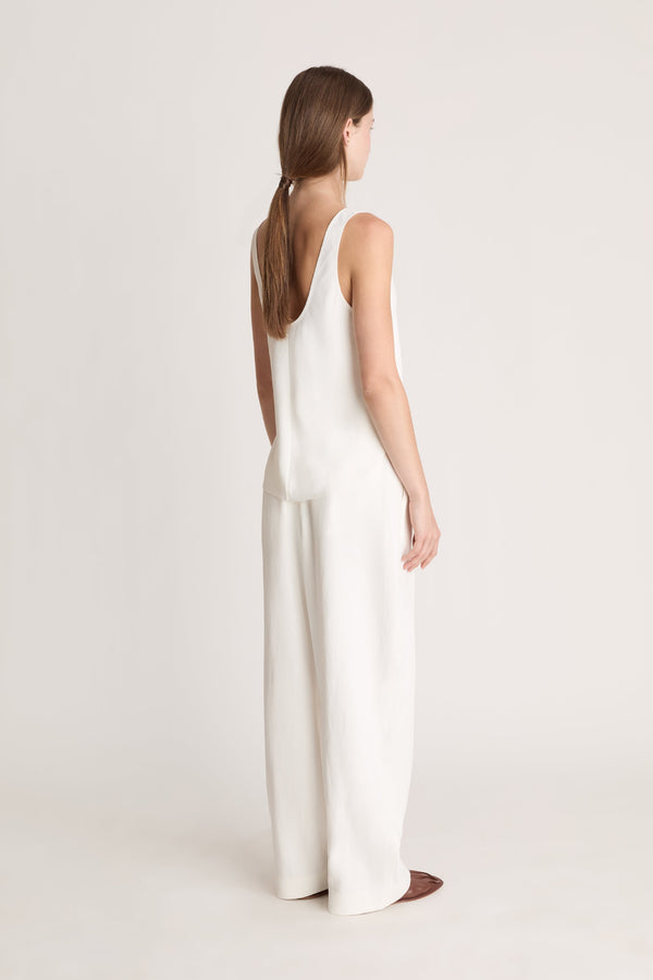 Woman wearing a white tank  top and white trousers on a white background