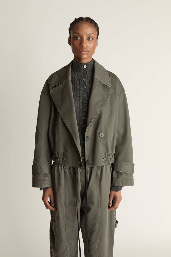 Person wearing a green coat and pants on a plain background