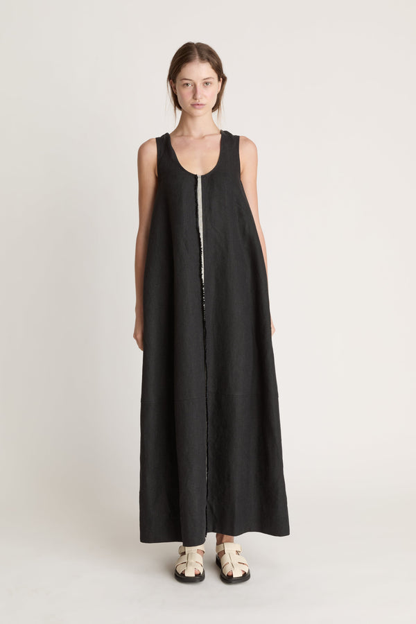 Woman wearing a black sleeveless dress with astripe down the front on a white background