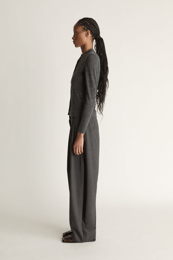 Woman wearing a grey cardigan and grey trousers on a white background