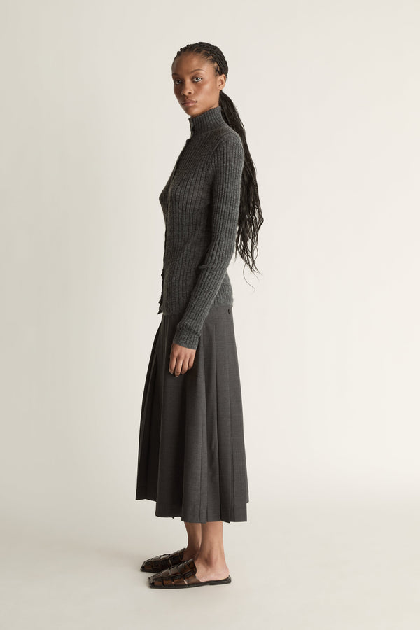 Woman wearing a gray ribbed sweater and skirt on a white background