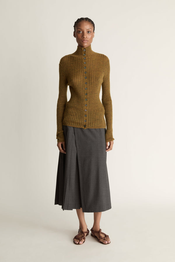 Woman wearing a brown ribbed sweater and gray skirt on a beige background