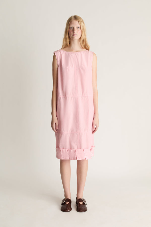 Woman facing the camera, wearing a pink silk dress midi dress against white background
