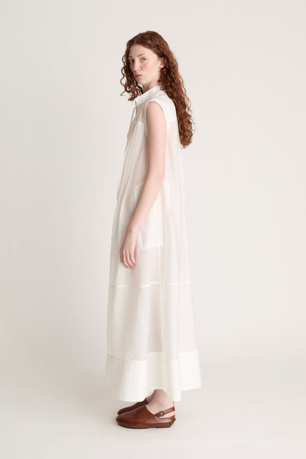 Woman wearing a long white dress with brown shoes on a white background