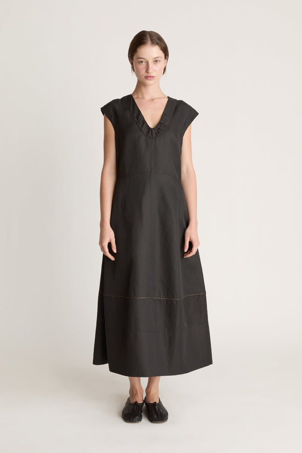 Woman wearing a black  v neck dress on a white background
