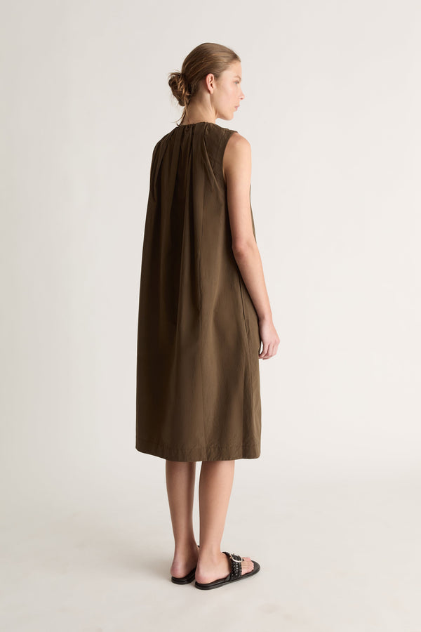 Back view of a woman with a bun in a khaki sleeveless midi dress with gathered back neckline