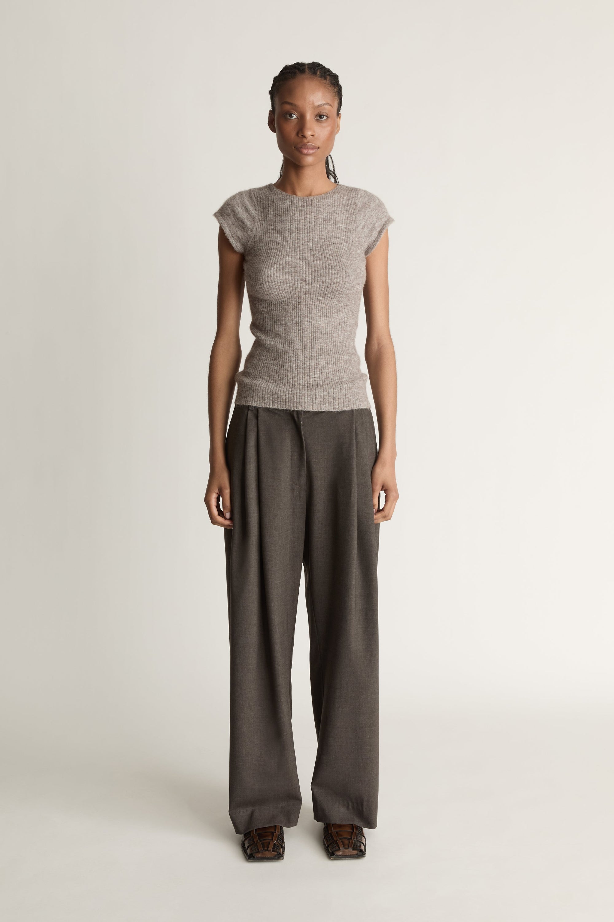 Woman wearing a gray sleeveless top and wide-leg pants on a white background