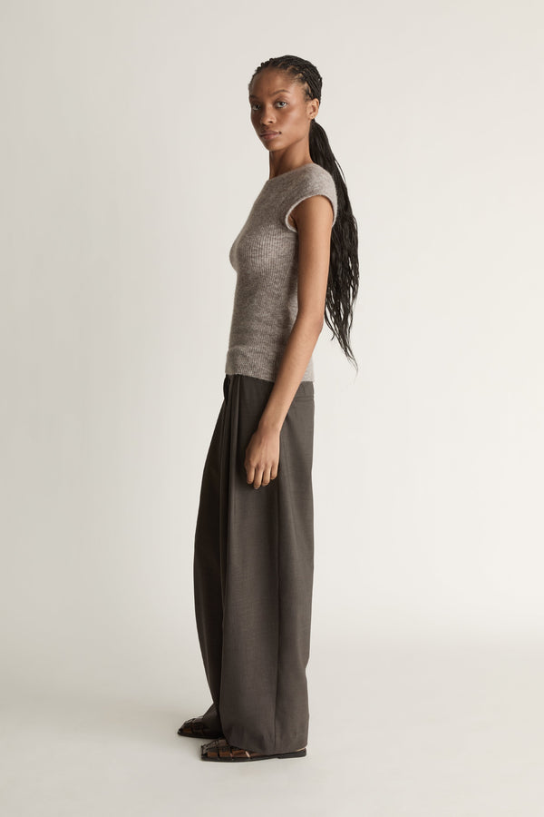Woman wearing a gray sleeveless top and wide-leg pants on a white background